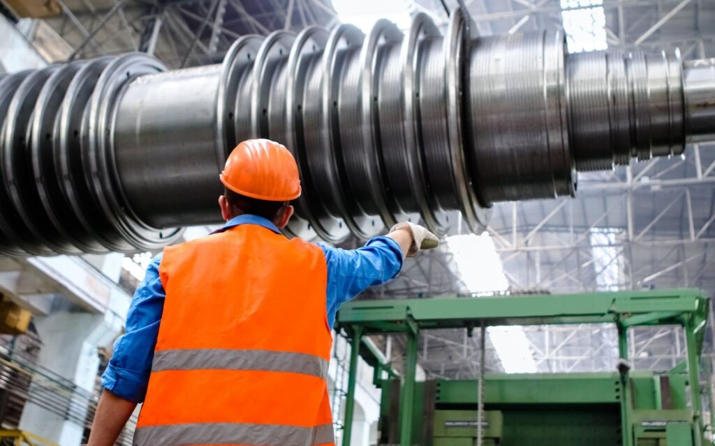Worker in an orange hard hat inspecting heavy machinery
